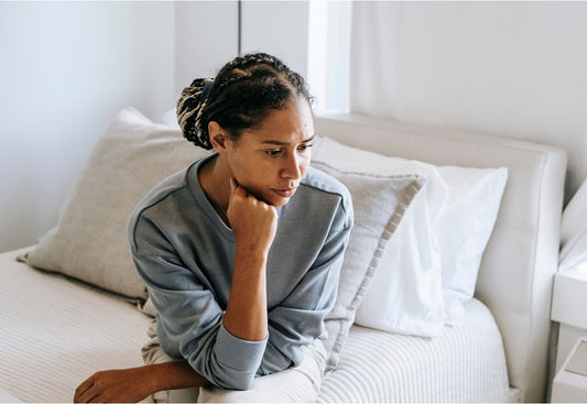 Woman sitting on the edge of her bed, unable to sleep despite exhaustion